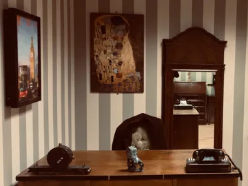 Holztisch mit Telefon, Bildern und einem Stuhl im Büro.